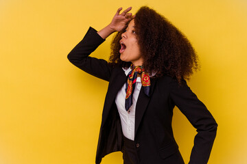 Young African American air hostess isolated on yellow background looking far away keeping hand on forehead.