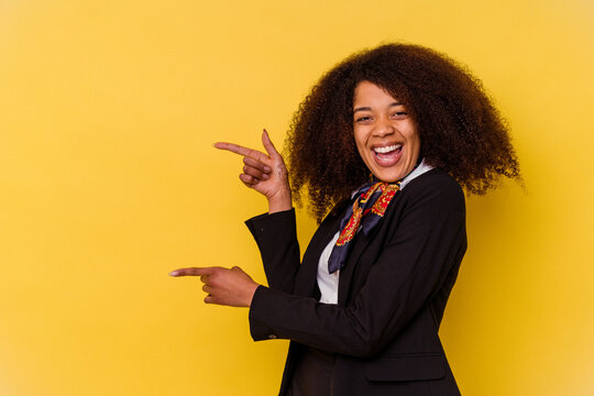 Young African American air hostess isolated on yellow background excited pointing with forefingers away.