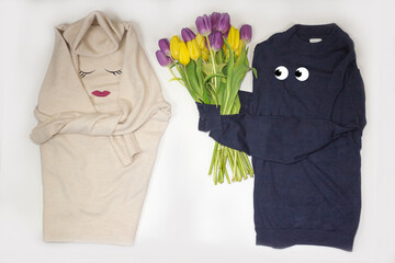 Humor. A man's sweater gives a bouquet of flowers to a woman's sweater.