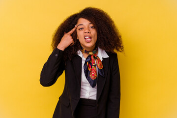 Young African American air hostess isolated on yellow background showing a disappointment gesture...