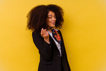 Young African American air hostess isolated on yellow background pointing with finger at you as if...