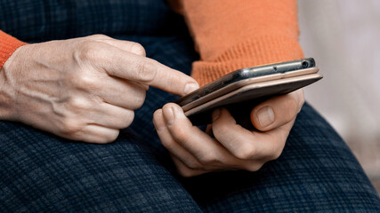 Elderly woman holding a mobile phone, communicating via the Internet