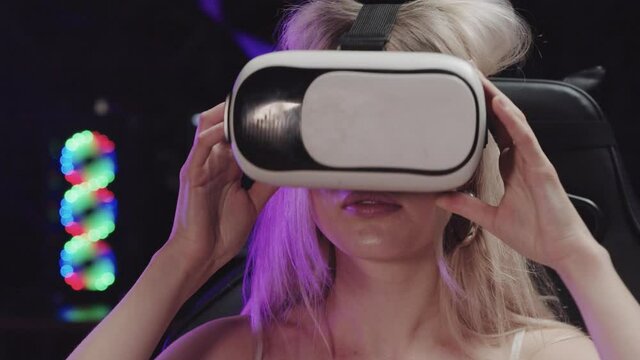 Attractive blonde gamer girl putting on VR glasses