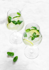Gin and tonic cocktail with lime and mint on a light background, top view
