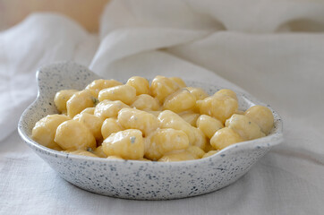 Small bowl with potato gnocchi and gorgonzola cheese.