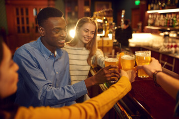 Four cheerful friends drinks beer in bar