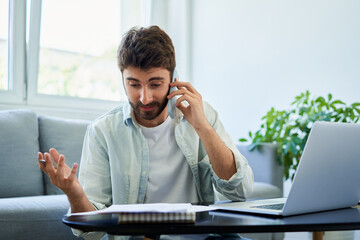 Unhappy man discussing bills over phone. Home finances concept.