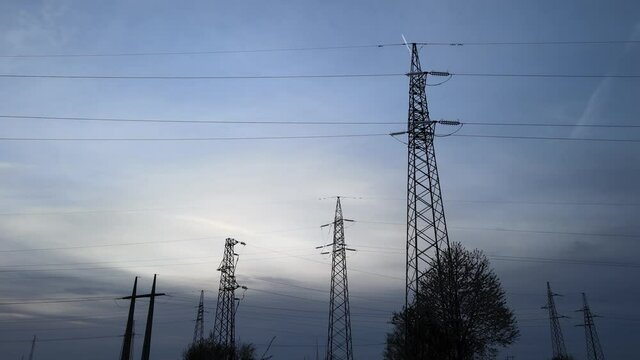 Silhouette Electrical pylons , with a plane on cloudy dusk sky - Tracking view