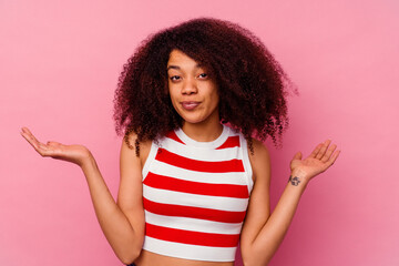 Young african american woman isolated on pink background confused and doubtful shrugging shoulders to hold a copy space.