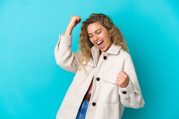 Young blonde woman isolated on blue background celebrating a victory