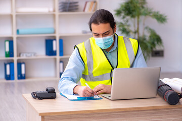 Young male architect working in the office during pandemic