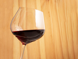 Elegant wineglass with red wine on bright vintage wooden background