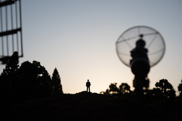 Creative artwork decoration. Silhouette of mobile air defence truck with radar antenna during sunset. Satellite dishes or radio antennas against evening sky.