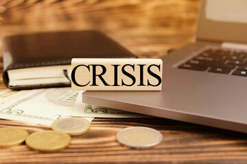 Computer, notebook, pen, crisis, money. Cubes with the word "crisis" on the computer in the office