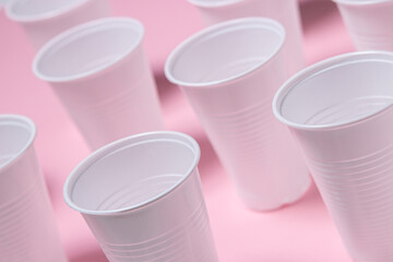 Plastic glasses on a pink background. Disposable tableware. Plastic products.
