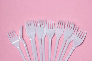 Plastic forks on a pink background. Disposable tableware. Plastic products.
