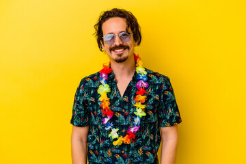 Young caucasian man wearing a hawaiian necklace isolated on yellow background happy, smiling and...