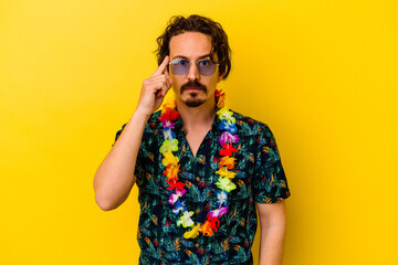 Obraz premium Young caucasian man wearing a hawaiian necklace isolated on yellow background pointing temple with finger, thinking, focused on a task.