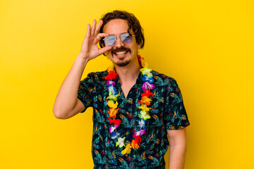 Young caucasian man wearing a hawaiian necklace isolated on yellow background excited keeping ok...