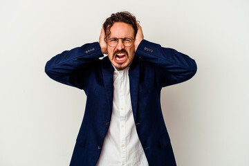 Young business man isolated on white background covering ears with hands trying not to hear too loud sound.