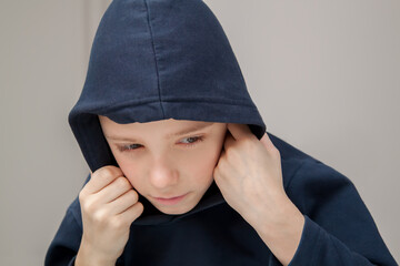 young sad boy in hood looking down and worried of problem at school. Bullying, depression, child protection or loneliness concept