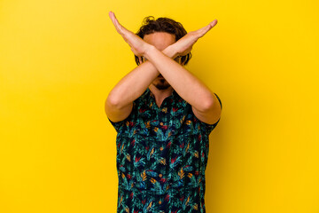 Young caucasian man wearing summer clothes isolated on yellow background keeping two arms crossed,...