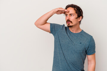 Young caucasian man isolated on white background looking far away keeping hand on forehead.