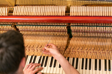 Piano tuning process. closeup of hand and tools of tuner working on grand piano. Detailed view of...