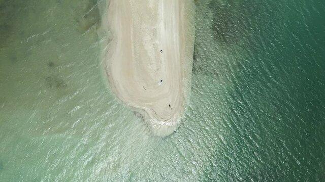 Descending aerial view of a bikini model laying in the white sand beach of No Man Land, Tobago