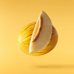 Fresh raw melon falling in the air isolated on yellow