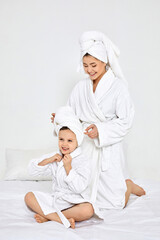 beautiful mother and daughter in white bathrobes and towels