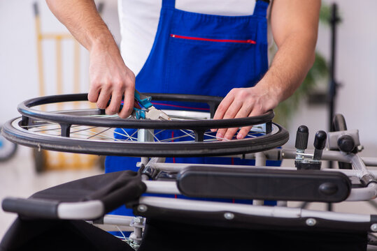 Young male repairer repairing wheel-chair indoors