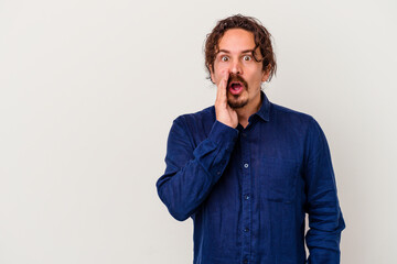 Obraz premium Young caucasian man isolated on white background is saying a secret hot braking news and looking aside