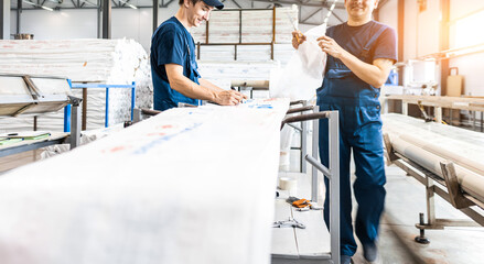 Workers in a factory carry out technological processes on a conveyor line in protective overalls