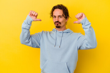 Young caucasian man isolated on yellow background feels proud and self confident, example to follow.