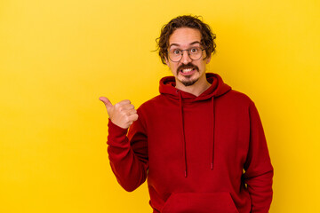 Young caucasian man isolated on yellow background shocked pointing with index fingers to a copy space.