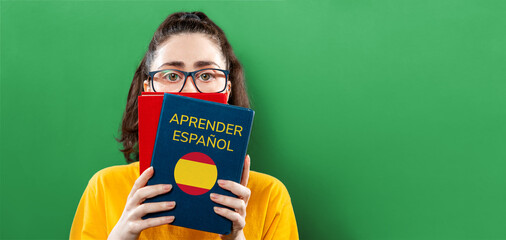 The concept of learning foreign languages. Portrait of a young woman holding books on learning...