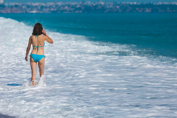 A girl in a swimsuit walks along the beach