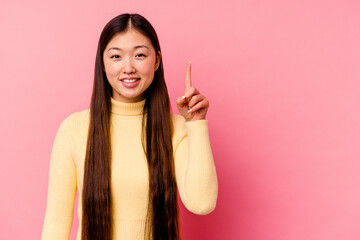 Young chinese woman isolated on pink background showing number one with finger.