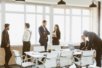 Silhouettes of people against the window. A team of young businessmen working and communicating together in an office. Corporate businessteam and manager in a meeting.