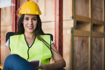 Young beautiful Hispanic Latin woman worker sit near shelf product box in big warehouse factory store which smile and felling happy, logistic import and export transportation concept