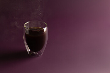 espresso morning coffee in glass cup with steam on a purple background