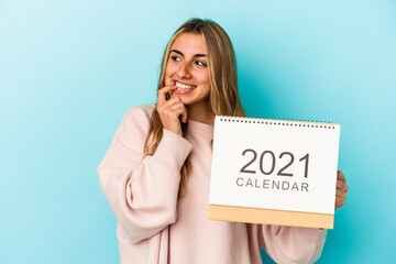 Young blonde caucasian woman holing a calendar isolated relaxed thinking about something looking at a copy space.