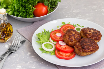 Fried meat cutlets with tomatoes and salad on a plate.