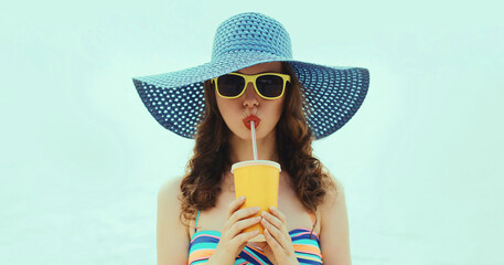 Woman drinking a juice wearing a straw hat on a beach on a sea background at summer day