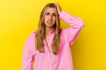 Young blonde caucasian woman isolated on yellow background forgetting something, slapping forehead with palm and closing eyes.