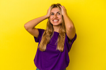 Fototapeta premium Young blonde caucasian woman isolated on yellow background laughs joyfully keeping hands on head. Happiness concept.