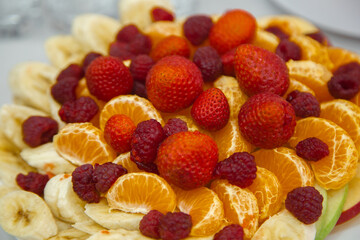 Fruit plate consisting of banana, Apple, Mandarin, strawberry and raspberry.