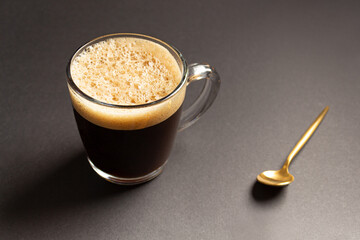 espresso morning coffee in glass cup with steam on a black background
