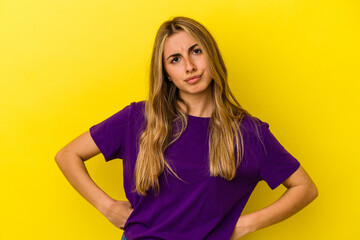 Young blonde caucasian woman isolated on yellow background confused, feels doubtful and unsure.